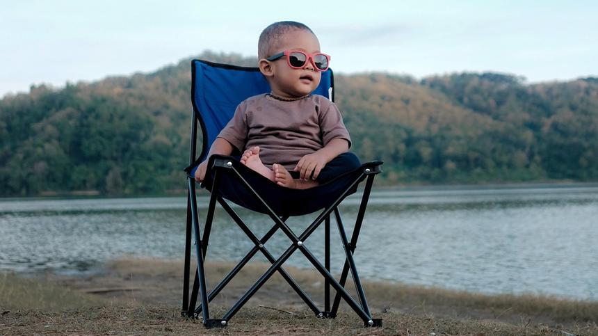 Baby trägt eine Sonnenbrille und sitzt auf einem Stuhl