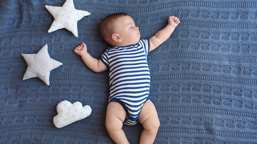 Baby liegt auf blauer Decke mit Stoffsternen