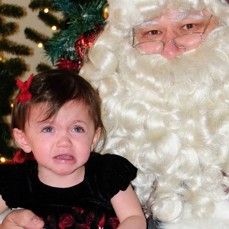 Kleines Mädchen mit roter Schleife im Haar weint wegen Weihnachtsmann