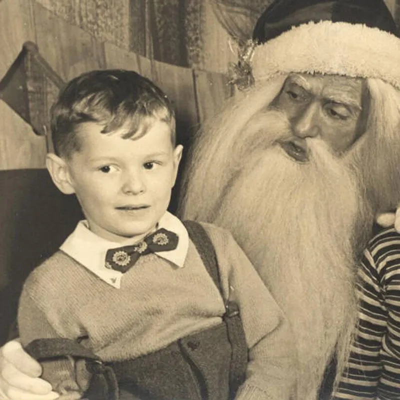 Altes Schwarz-Weiß-Foto vom Kind auf dem Schoß vom Weihnachtsmann