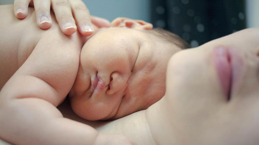 Baby liegt auf der Brust seiner Mutter