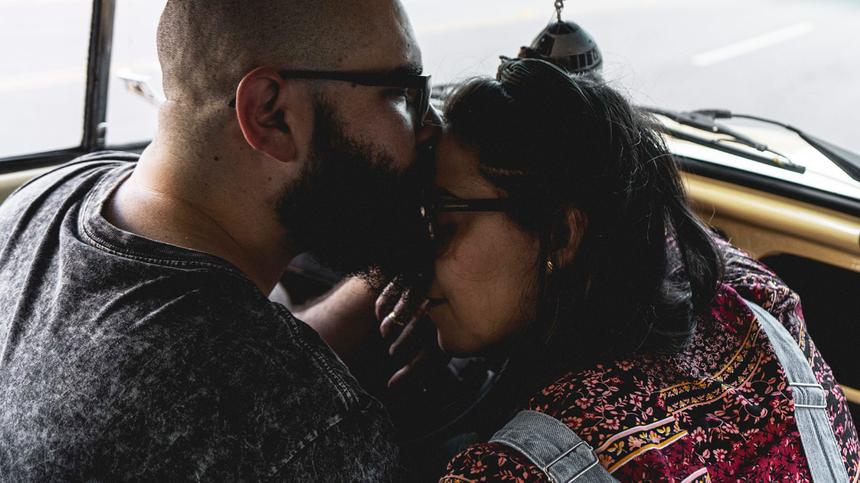 Mann mit Bart küsst seiner Frau auf die Stirn