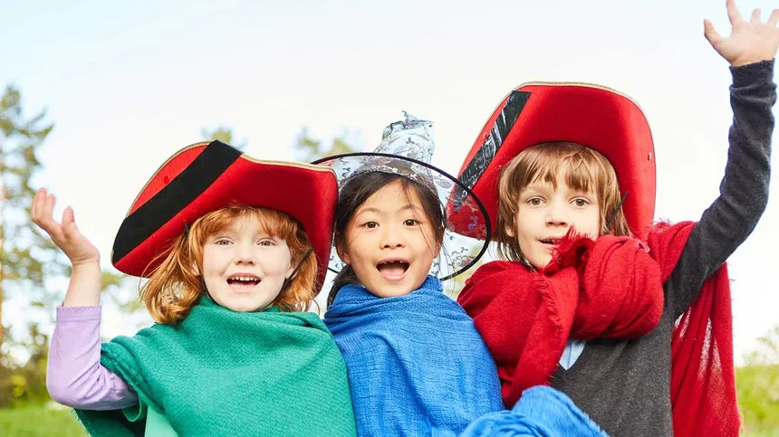 Drei Kinder in Kostümen schauen in die Kamera