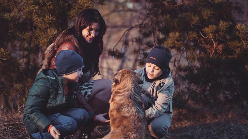 Mutter, zwie Jungen und ein Hund spielen im Wald
