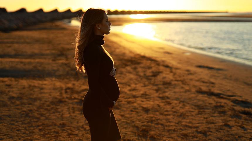 Schwangere steht am Strand