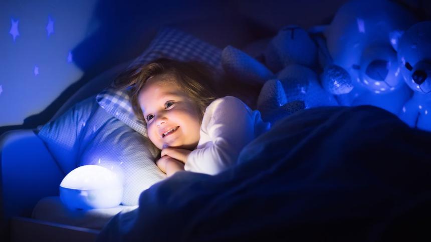 Kind liegt mit einem Nachtlicht im Bett