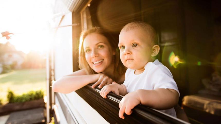 Mama schaut mit Baby aus einem Wohnmobil-Fenster
