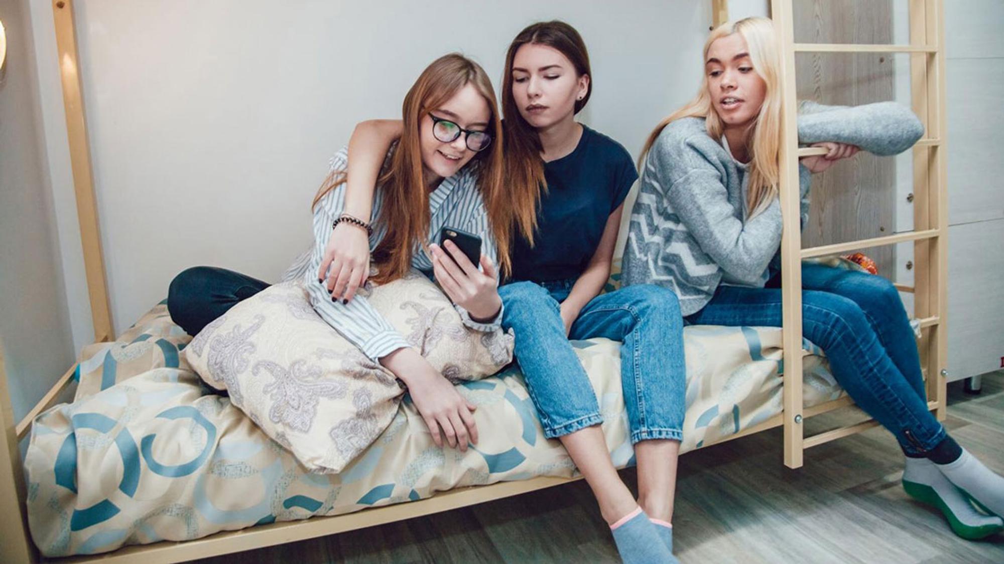 Drei Freundinnen sitzen zusammen und schauen auf ein Handy