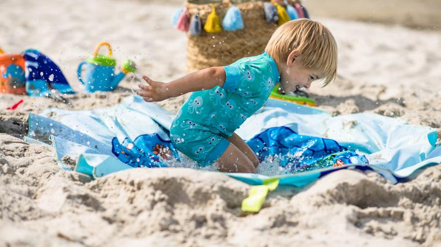 Junge spielt auf einer Strandpooldecke