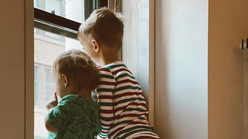 Zwei Kinder schauen aus dem Fenster