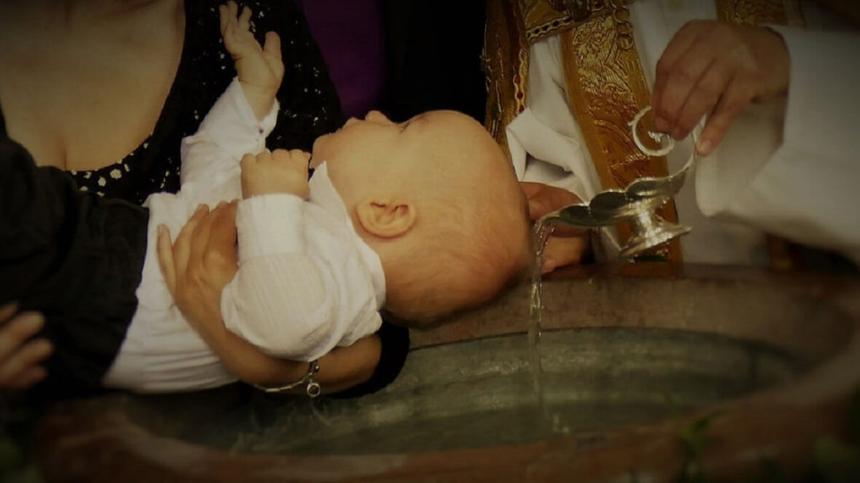 Ein Kind empfängt die Taufe über dem Taufbecken