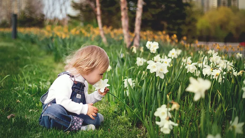 Kind sitzt vor Blumen