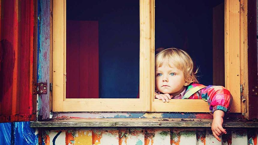 Kind steht an einem offenen Fenster