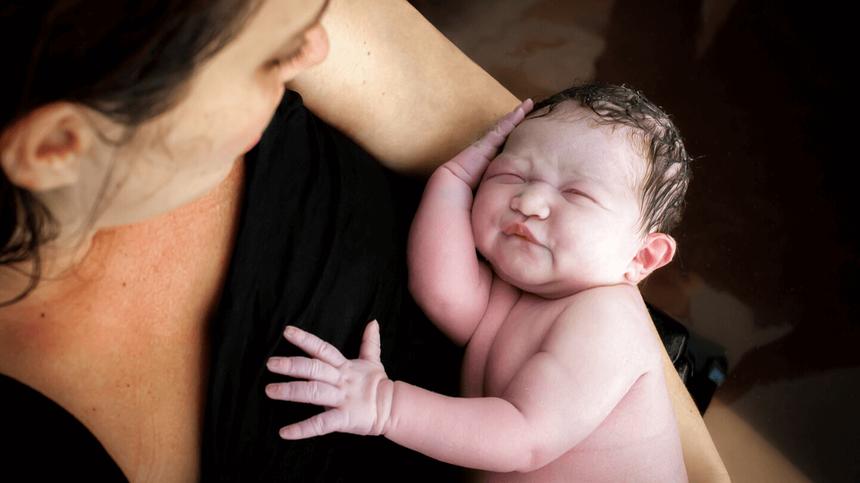 Frau hält ihr Baby kurz nach der Geburt im Arm