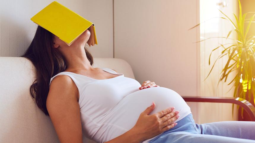 Schwangere Frau schläft mit dem Buch auf dem Gesicht
