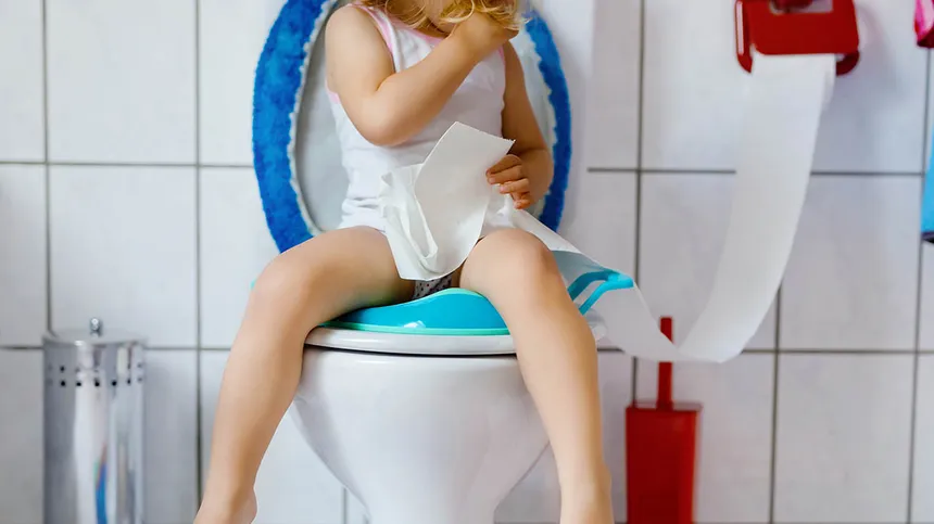 Mädchen sitzt auf einer Toilette