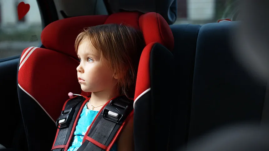 Mädchen im Kindersitz schaut aus dem Autofenster