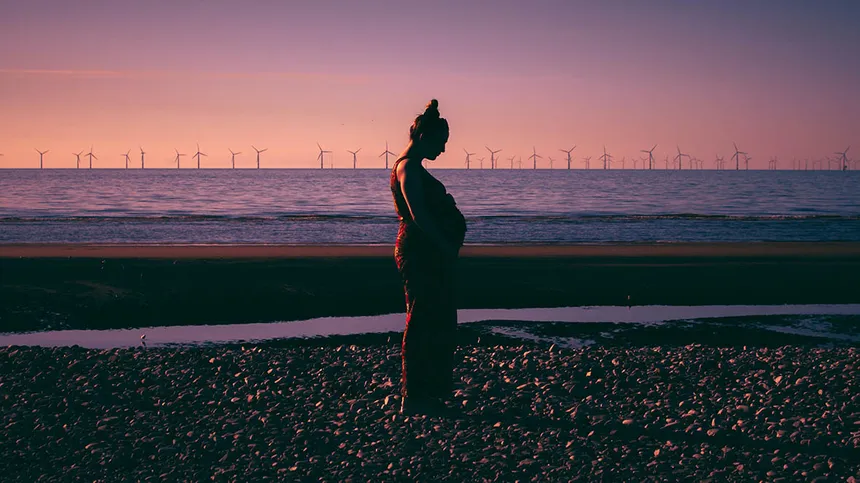 Zu wenig Fruchtwasser: Frau steht bei Sonnenuntergang am Wasser