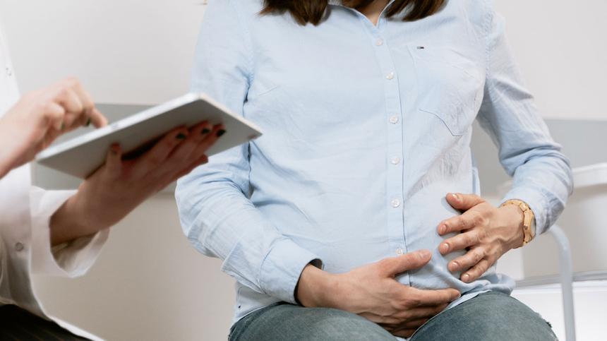 Schwangere Frau sitzt beim Frauenarzt