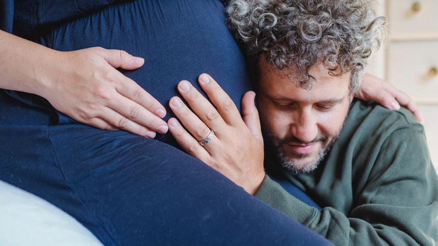 Mann hört am Babybauch einer Schwangeren