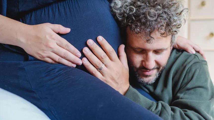 Mann hört am Babybauch einer Schwangeren