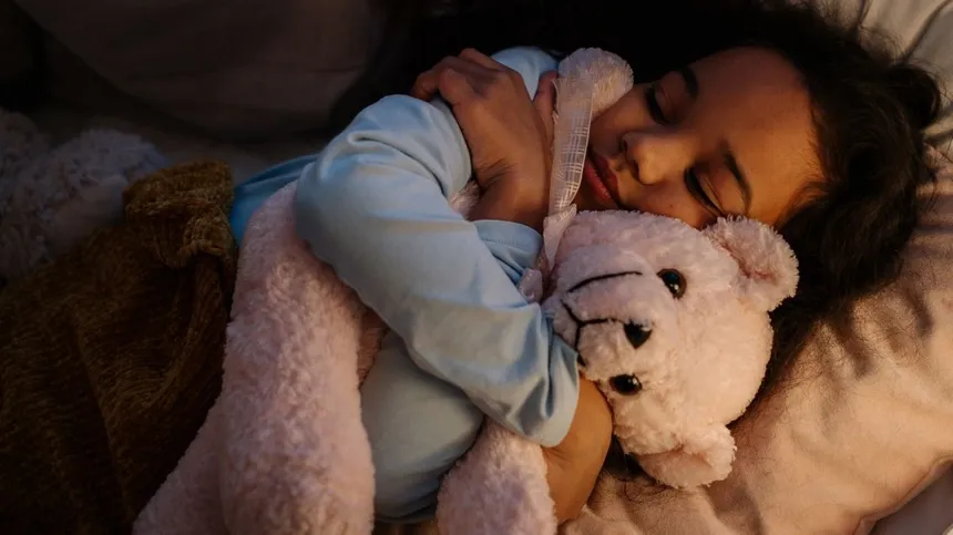 Kind hält Kuscheltier zum Einschlafen fest im Arm