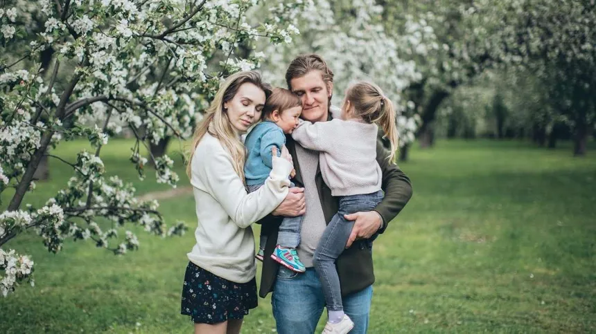 Familie mit zwei Kindern vor einem Kirschbaum im Garten