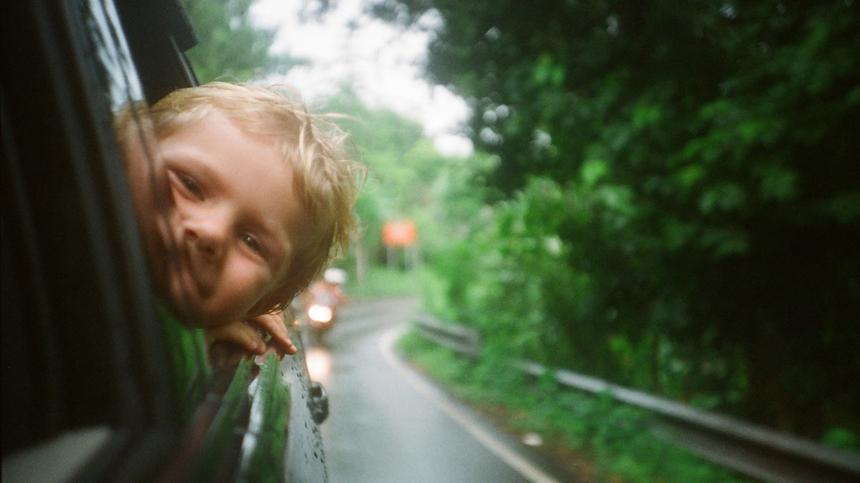 fröhliche Kind schaut aus fahrendem Auto