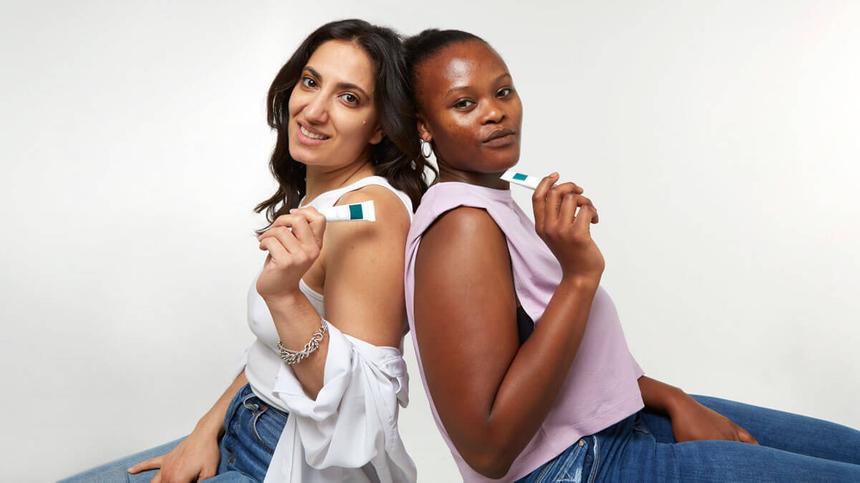 Zwei Frauen sitzen Rücken an Rücken und halten FORMEL SKIN Produkte