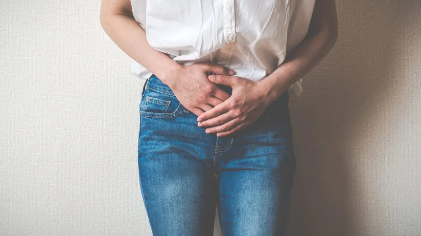 Gebärmutterhalskrebs erkennen: Frau hält Hände auf den Unterbauch