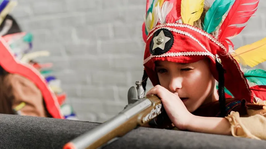Kind trägt Indianer Kostüm mit Federschmuck