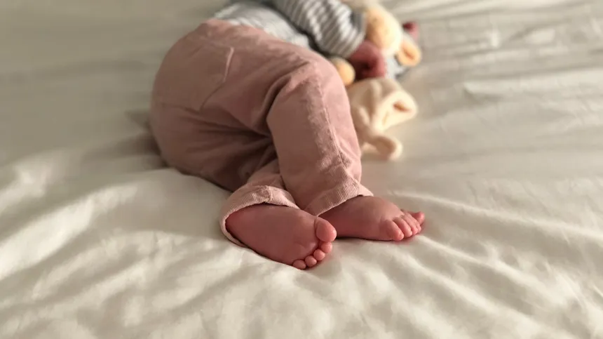 Ein Baby liegt schlafend auf einem Bett