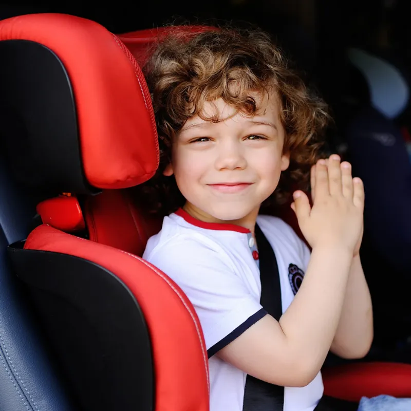 Junge sitzt lächelnd im Kindersitz im Auto