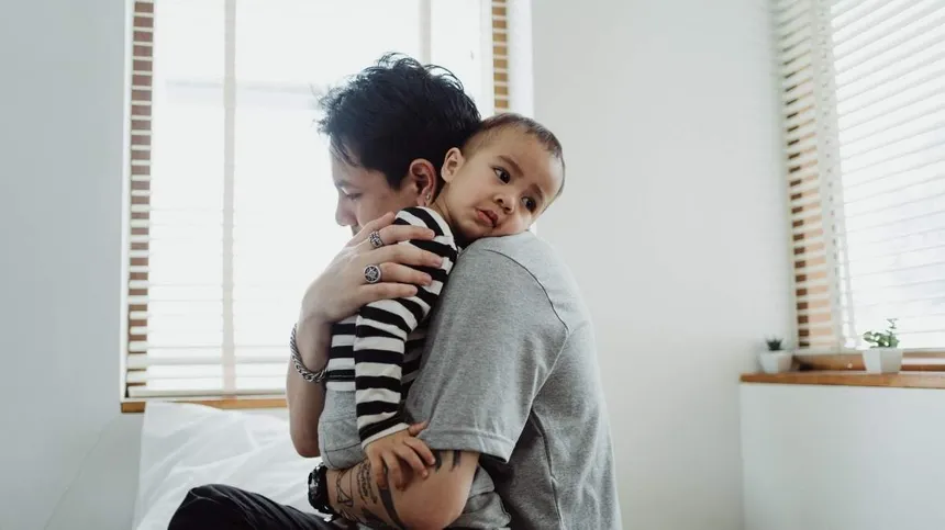 Kind mit Sommergrippe kuschelt sich in Papas Arm