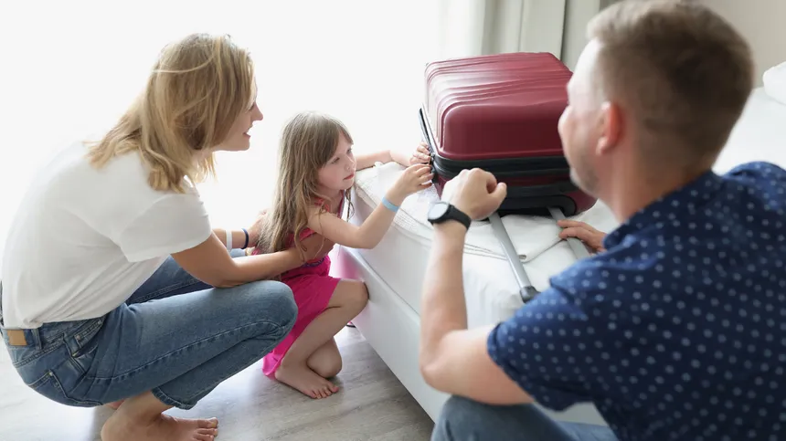 Familie öffnet im Urlaub ihren Koffer auf dem Hotelbett