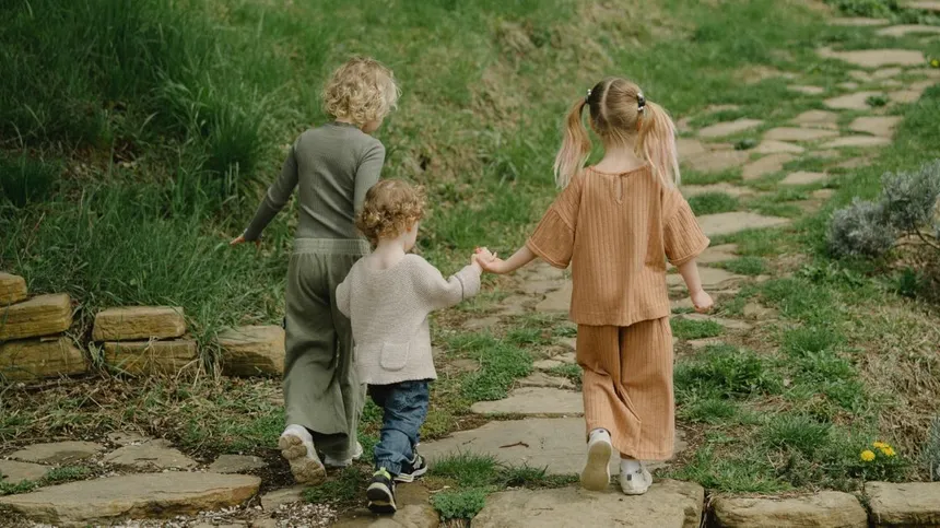 Drei Kinder halten sich beim Spazieren gehen an den Händen