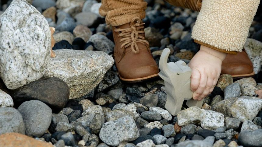 Kinderhand mit Spielzeug auf Steinen