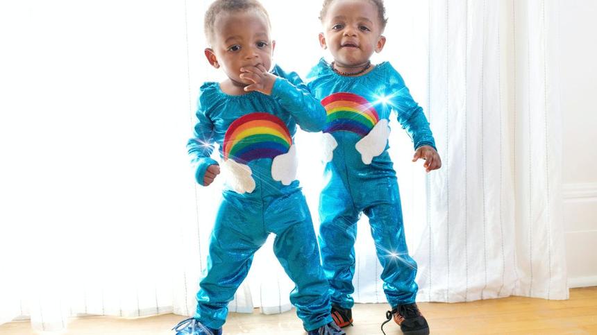 Zwillinge stehend im Regenbogenkostüm