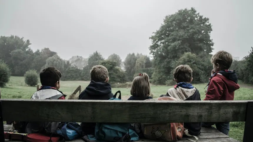 Fünf Kinder sitzen auf einer Bank. Sie sind nur von Hinten erkennbar.