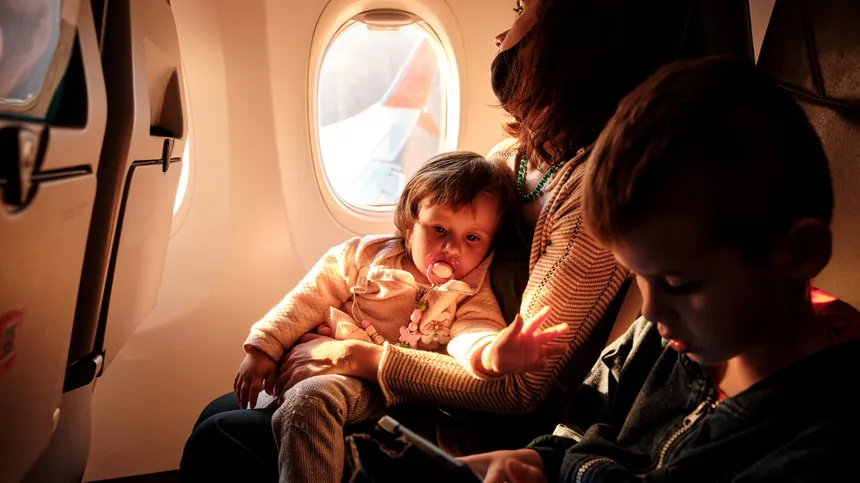 Mutter mit Baby und Kleinkind im Flugzeug