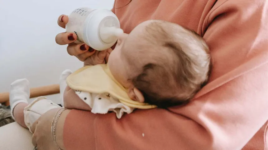 Mama füttert Baby mit Kuhmilchallergie mit der Flasche