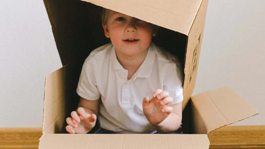 Kind sitzt in einem großen Karton