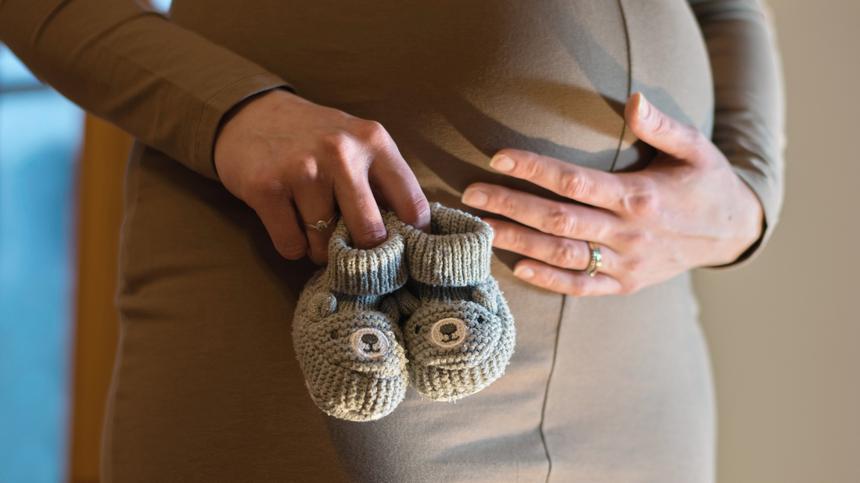Schwangere Frau hält Babyschuhe in der Hand