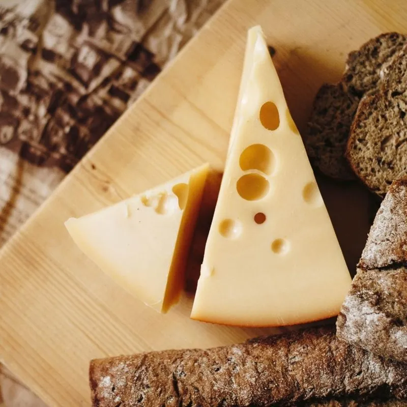 Zwei Stücke Käse mit Brot auf einem Holzbrett