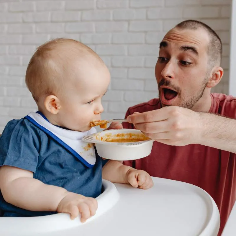Papa füttert dem Baby die erste Beikost