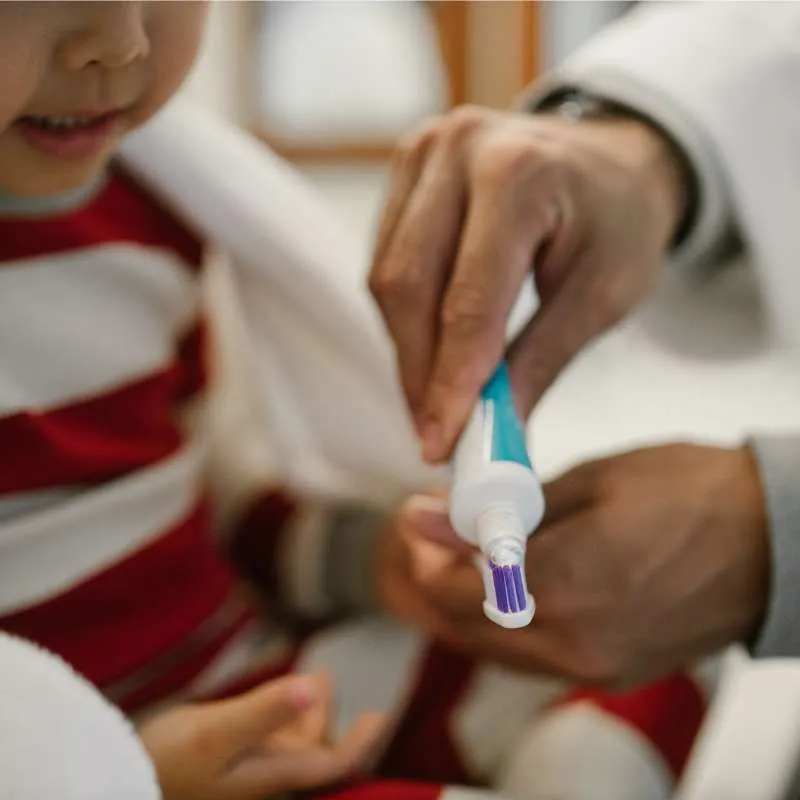 Kind und Papa drücken Zahnpasta auf die Zahnbürste