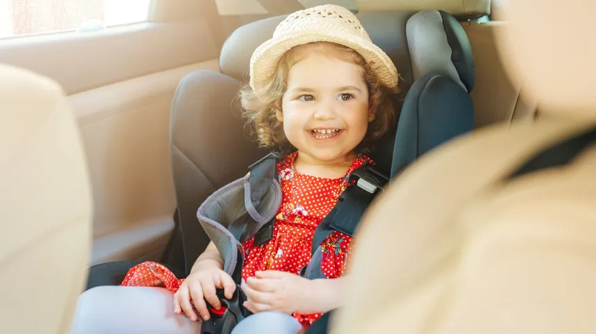 Kind sitzt im Auto-Kindersitz und lacht