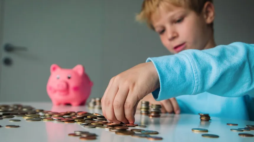 Junge sortiert Geldmünzen aus seinem Sparschwein